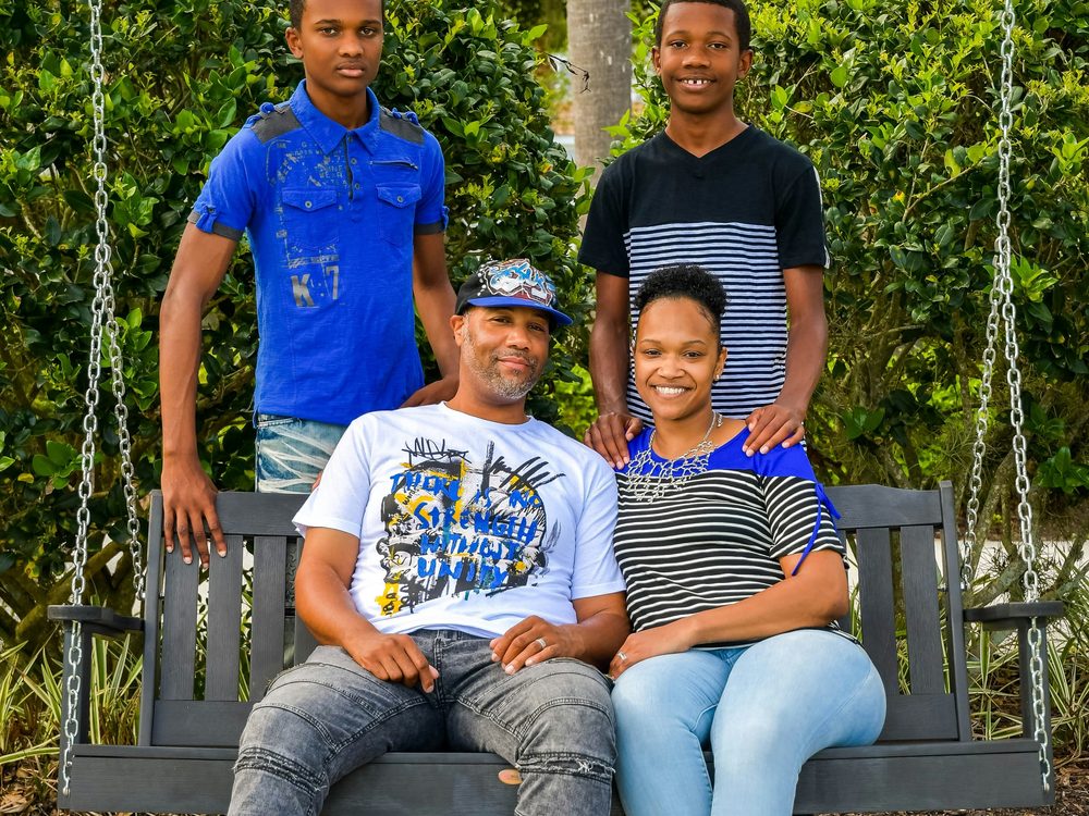 A family of four together on a porch swing.